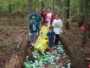 A group of volunteers getting ready to pick up a large pile of aluminum cans between two logs.