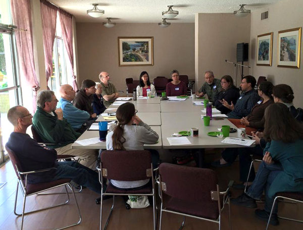 The FOSC Roundtable meeting around a large table in a bright conference room with windows along one side..