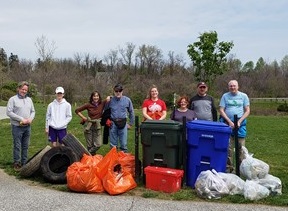 A group of people who have picked up trash at Piney Branch and Sligo Creek including tires, old lumber, and bins full of recyclables.