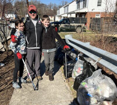 A dad and two energetic helpers with grabbers and trash they collected.