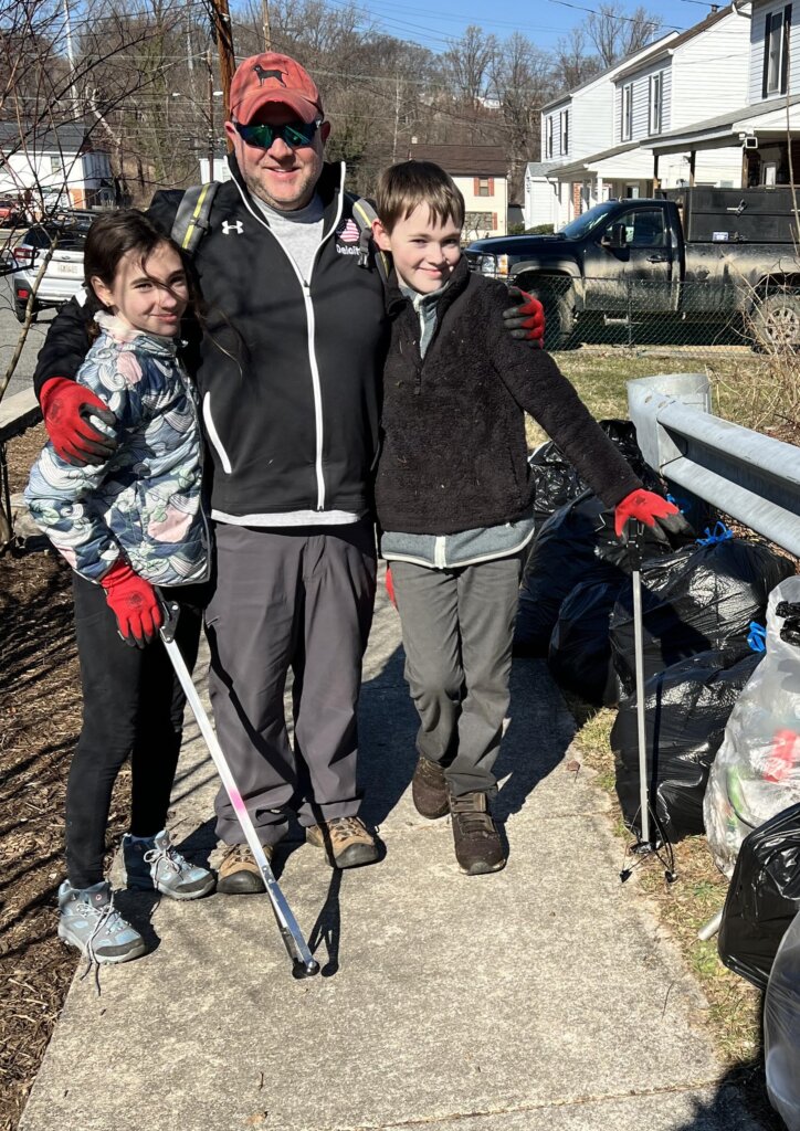 A dad and two energetic helpers with grabbers and trash they collected.